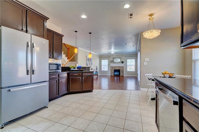 kitchen featuring dark countertops, dark brown cabinetry, stainless steel appliances, and open floor plan