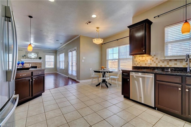 kitchen with visible vents, a sink, stainless steel appliances, decorative backsplash, and dark brown cabinets