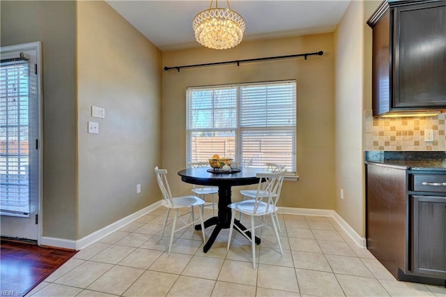 dining space featuring baseboards, a notable chandelier, and light tile patterned flooring