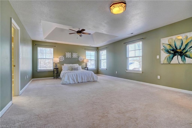 unfurnished bedroom with ceiling fan, baseboards, carpet, a tray ceiling, and a textured ceiling