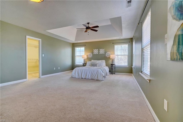 carpeted bedroom featuring visible vents, a textured ceiling, baseboards, and a tray ceiling