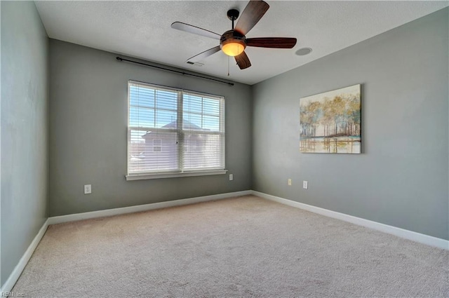 carpeted empty room featuring ceiling fan, a textured ceiling, and baseboards