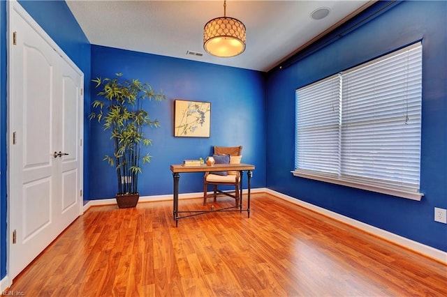 home office with wood finished floors, visible vents, and baseboards