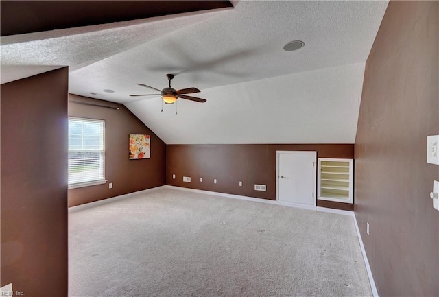 additional living space with a textured ceiling, carpet, ceiling fan, and vaulted ceiling