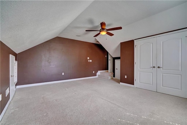 additional living space with baseboards, carpet floors, lofted ceiling, ceiling fan, and a textured ceiling