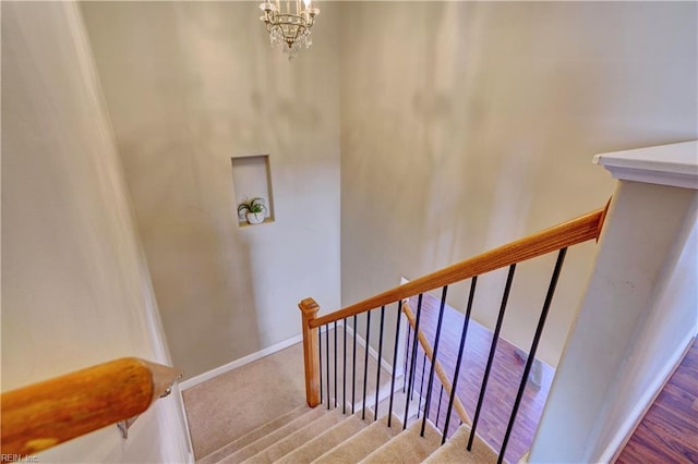 stairs with a notable chandelier, baseboards, and carpet floors