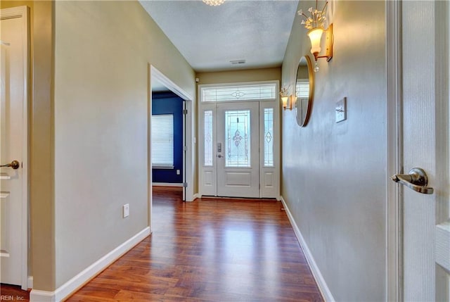 entrance foyer featuring visible vents, baseboards, a textured ceiling, and wood finished floors