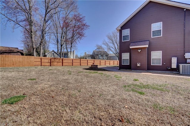 rear view of property featuring a yard, a fenced backyard, and central AC