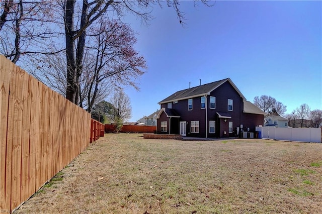 rear view of house with a yard and a fenced backyard