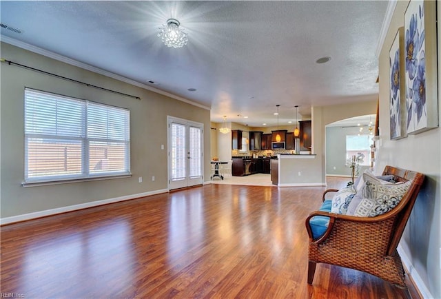 living area with visible vents, baseboards, arched walkways, dark wood-style flooring, and ornamental molding