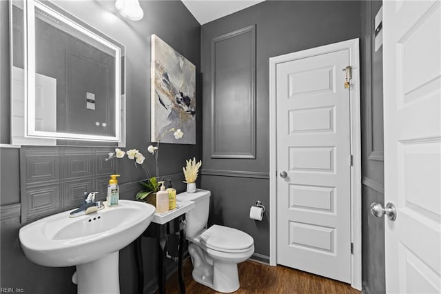 bathroom featuring a sink, toilet, and wood finished floors