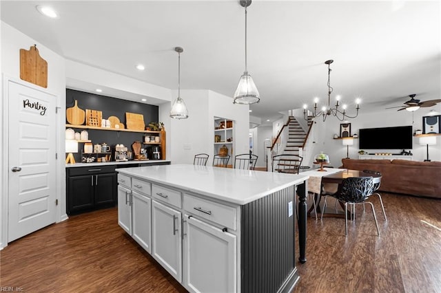 kitchen featuring hanging light fixtures, dark wood-type flooring, light countertops, and open floor plan