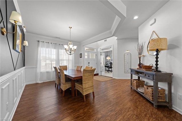 dining room featuring a notable chandelier, wood finished floors, a decorative wall, and ornamental molding