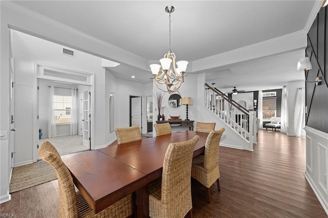 dining space with stairway, ceiling fan with notable chandelier, crown molding, and wood finished floors