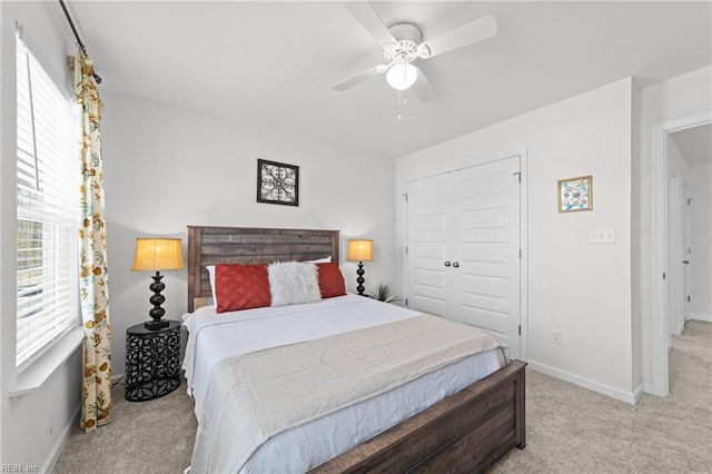 bedroom with a closet, light carpet, baseboards, and a ceiling fan