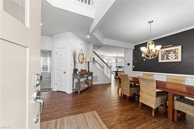 dining space featuring wood finished floors, visible vents, an inviting chandelier, stairs, and crown molding