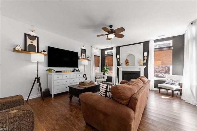 living room with baseboards, a ceiling fan, wood finished floors, and a fireplace