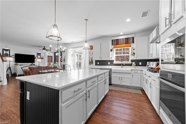 kitchen featuring oven, visible vents, a sink, white cabinetry, and dark wood-style flooring