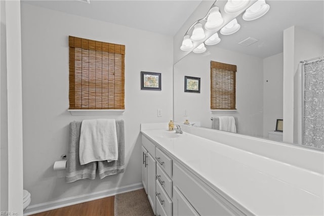 full bath featuring vanity, toilet, visible vents, and baseboards