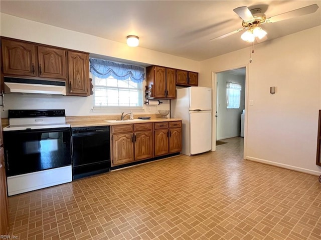 kitchen featuring under cabinet range hood, dishwasher, light countertops, electric range oven, and freestanding refrigerator