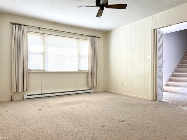 carpeted empty room with stairway, a textured ceiling, a ceiling fan, and a baseboard radiator