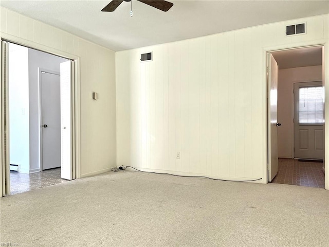 spare room featuring carpet flooring, visible vents, baseboard heating, and ceiling fan