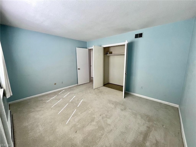 unfurnished bedroom with a closet, visible vents, a textured ceiling, and baseboards