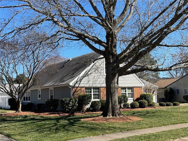 view of front of house with a front yard, brick siding, and a shingled roof