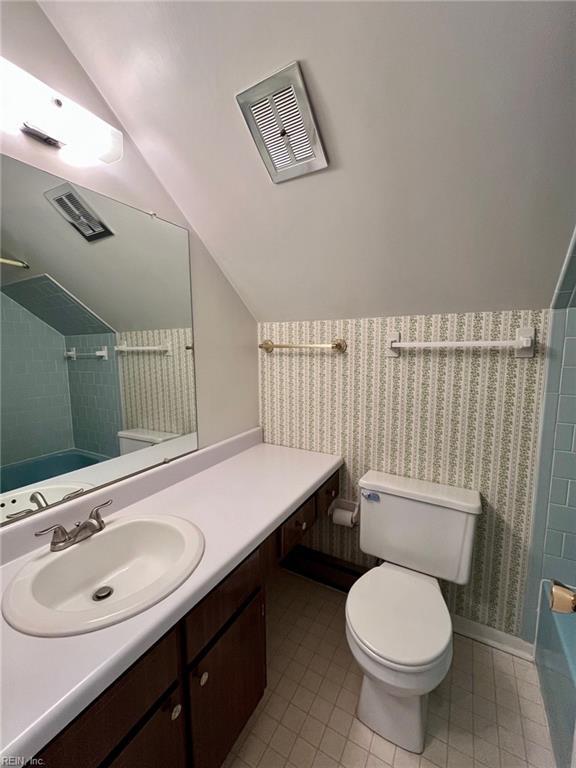 bathroom with tile patterned floors, visible vents, toilet, vanity, and vaulted ceiling