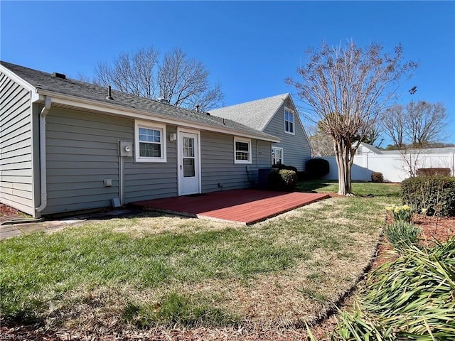 back of property with a wooden deck, a lawn, and fence