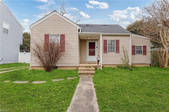 view of front of property with a shingled roof, a front lawn, and fence