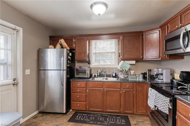 kitchen featuring a sink, dark countertops, stone finish flooring, and stainless steel appliances