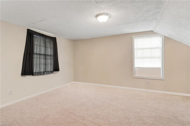 carpeted spare room with baseboards, a textured ceiling, and lofted ceiling