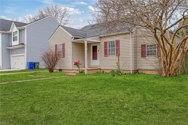 view of front of house with a front lawn, an attached garage, and roof with shingles