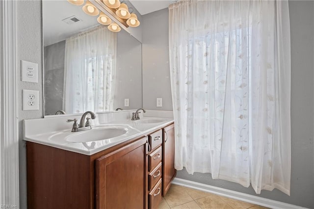 bathroom featuring tile patterned floors, visible vents, double vanity, and a sink