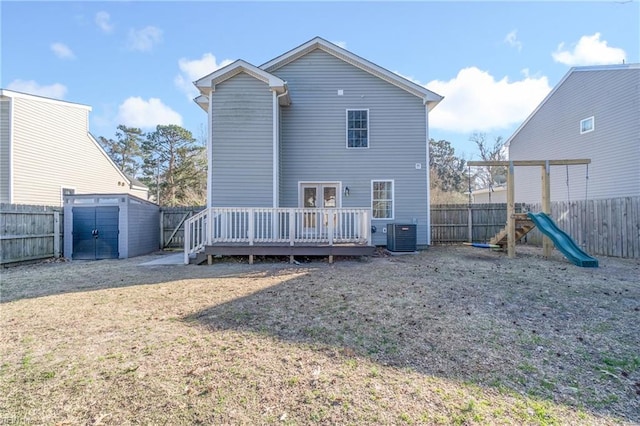 rear view of property featuring cooling unit, a yard, a fenced backyard, a deck, and a playground