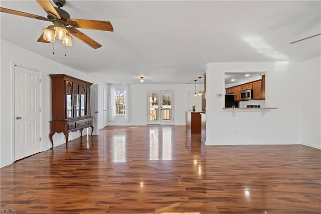 unfurnished living room featuring wood finished floors, baseboards, french doors, and ceiling fan