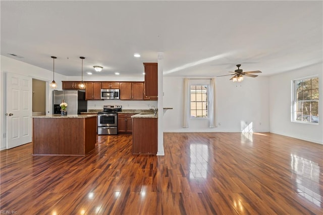 kitchen featuring dark wood-type flooring, a sink, a kitchen island, open floor plan, and stainless steel appliances