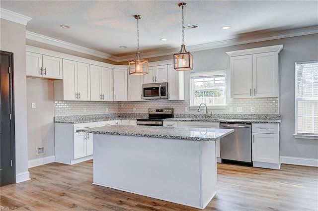 kitchen featuring light wood finished floors, a kitchen island, appliances with stainless steel finishes, and white cabinetry