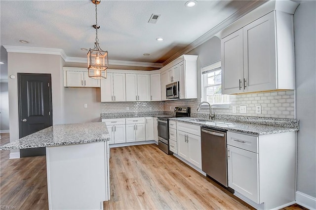 kitchen with visible vents, light wood finished floors, appliances with stainless steel finishes, white cabinetry, and a center island