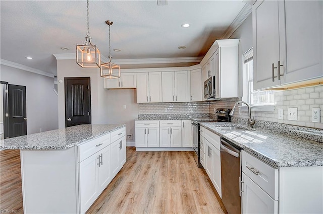 kitchen with a kitchen island, crown molding, appliances with stainless steel finishes, light wood-style floors, and a sink