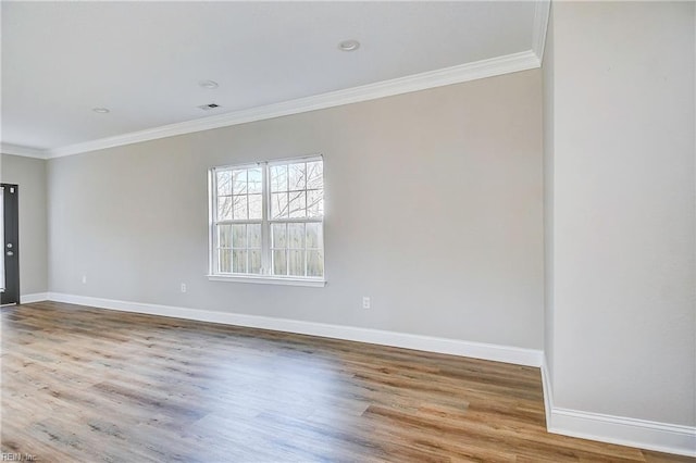 spare room featuring visible vents, wood finished floors, baseboards, and ornamental molding