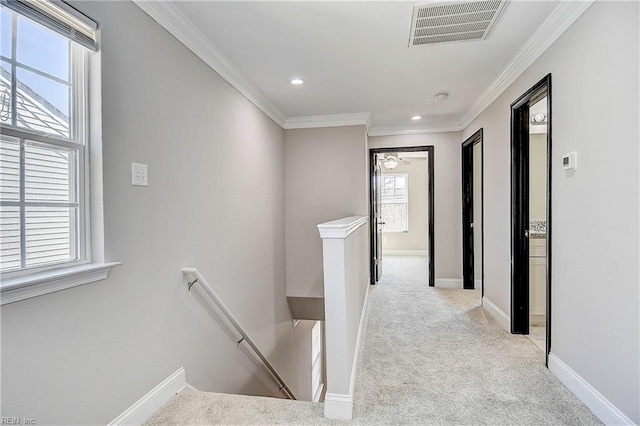 hallway featuring visible vents, baseboards, crown molding, carpet flooring, and an upstairs landing