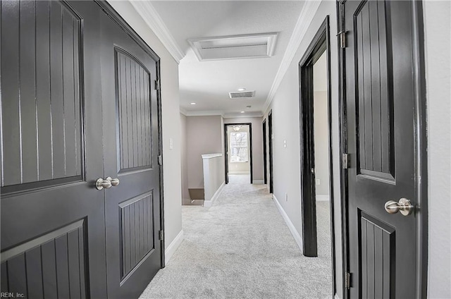 corridor with baseboards, visible vents, attic access, crown molding, and light colored carpet