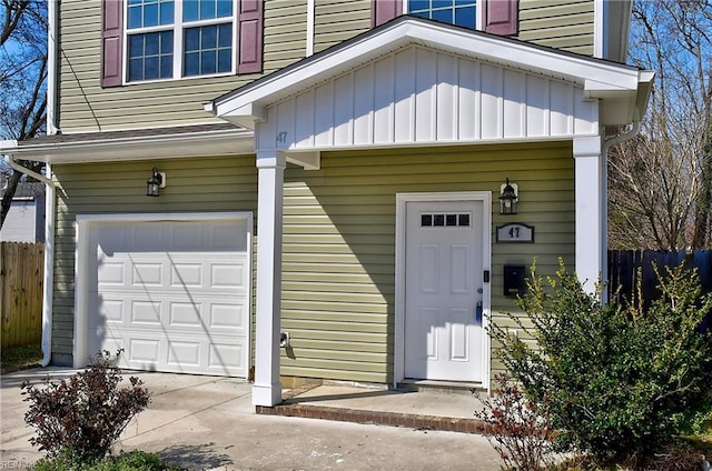 property entrance featuring driveway, board and batten siding, an attached garage, and fence