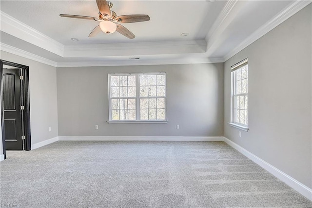 carpeted spare room featuring baseboards, a ceiling fan, a tray ceiling, and ornamental molding