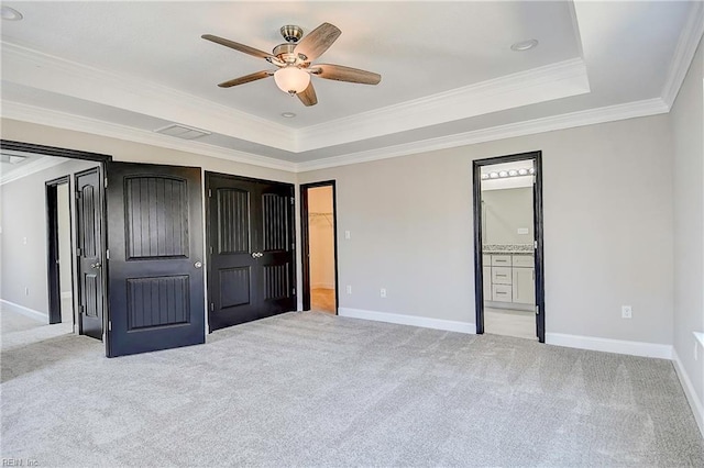 unfurnished bedroom featuring a tray ceiling, light carpet, baseboards, and crown molding