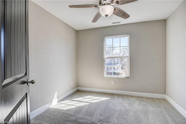 carpeted spare room featuring visible vents, a ceiling fan, and baseboards