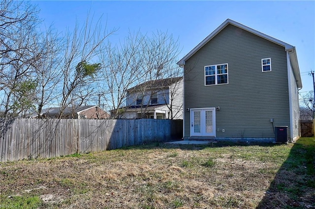 rear view of property featuring a yard, french doors, fence private yard, and central AC