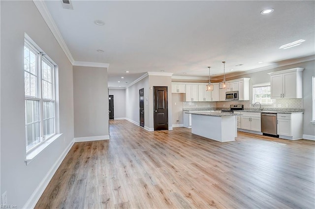 kitchen with backsplash, a kitchen island, light wood-style flooring, stainless steel appliances, and white cabinetry